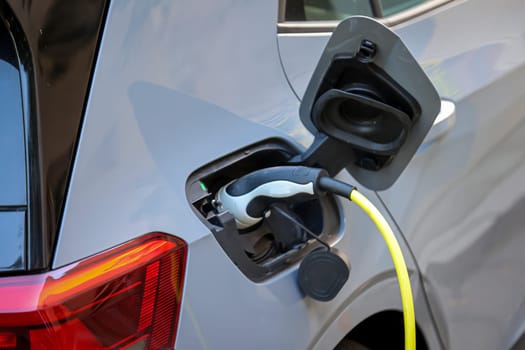 An electric car is charged at a charging station using a charging cable.