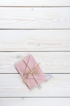 Pink envelope tied with rough jute rope on white wooden background. Copy space. Top view. Mail, correspondence, sending messages, congratulations. Vertical