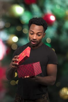 young man receiving a gift and opening box christmas night surprise holiday surprise decorations bokeh light
