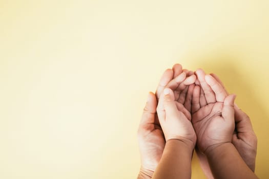 Closeup top view family hands stack palms studio shot isolated on yellow background, parents and kid holding empty free space on hand together, Gesture sign of support and love, Family and parents day