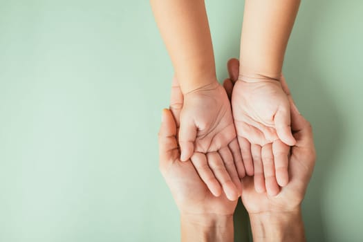 Closeup top view family hands stack palms studio shot isolated on green background, parents and kid holding empty free space on hand together, Gesture sign of support and love, Family and parents day