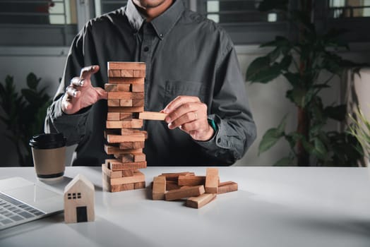 Alternative risk plan. Business hand playing tower wooden blocks game, man pull one wood block from tower he clenched his fist, show great joy in accomplishing it, Business gambling growth concept