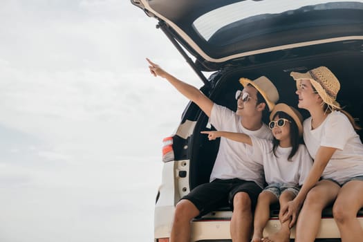 Happy Family Day. Family travel in holiday at sea beach, Dad, mom, daughter enjoy road trip sitting on back car and pointing finger out, people having fun in summer vacation on beach with automobile
