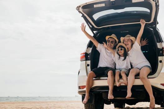 Happy Family Day. Dad, mom and daughter enjoying road trip sit on back car and raise hand up, Family traveling in holiday at sea beach, people having fun in summer vacation on beach with automobile