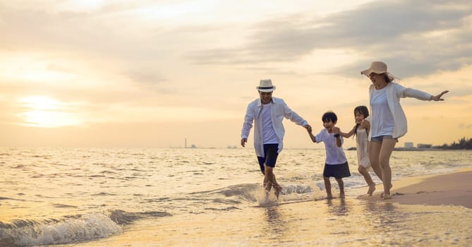 People of father, mother, children son and daughter family of four holding hands together walking outdoor, Happy family having fun running on a sandy beach at sunset, tropical summer travel vacations