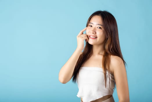 Close up woman smiling with natural makeup and healthy face, Asian young female with beauty face touching healthy facial skin studio shot isolated on blue background, Skin care and Beauty concept
