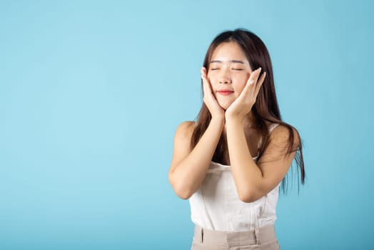 Beauty and Skin care. Beautiful woman model smiling with natural makeup and healthy face, Asian female with beauty face touching healthy facial skin studio shot isolated on blue background