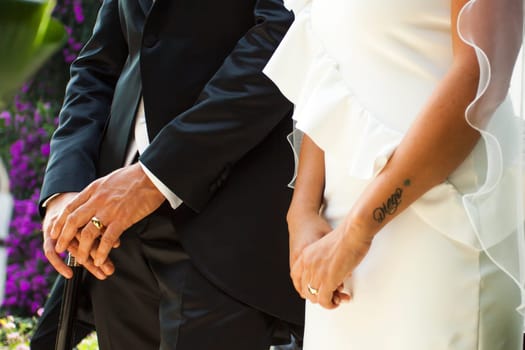 View a detail of the hands of the bride and groom with rings