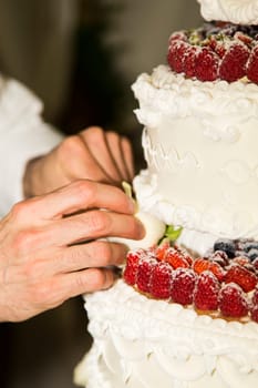 Close-up view of the hands of a baker whereas wedding cake adorned