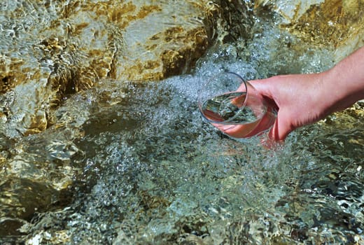 Woman's hand with water glass on a stream
