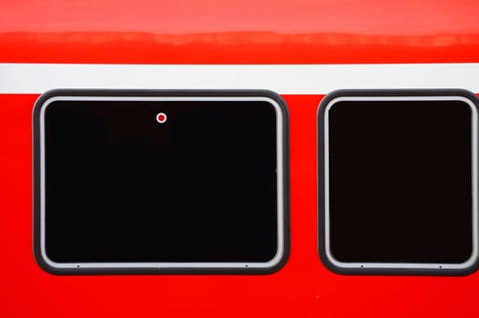 The close-up of the outer body of a passenger train with two windows.