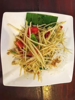 Papaya salad in a white plate, it is the staple food of Thai people.