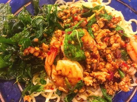 Stir fried ramen with basil in a blue plate.