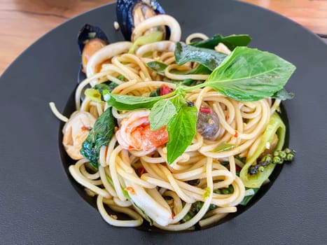 Drunken seafood spaghetti in a black plate.