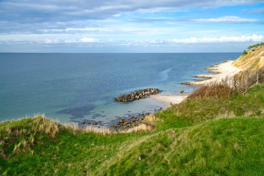 Hundested, Denmark on the cliff overlooking the sea. Baltic Sea coast, grassy meadow, beach. Clouds on horizon. Landscape photo from Scandinavia.