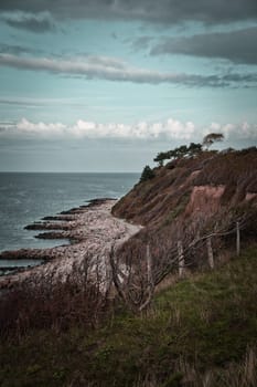Hundested, Denmark on the cliff overlooking the sea. Baltic Sea coast, grassy meadow, beach. Clouds on horizon. Landscape photo from Scandinavia.
