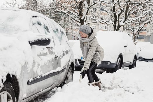 Independent woman shoveling her parking lot after a winter snowstorm.