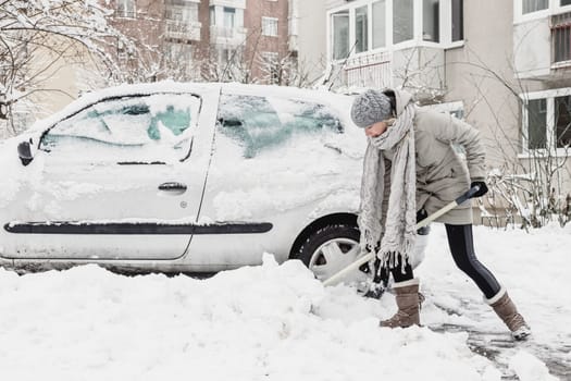 Independent woman shoveling her parking lot after a winter snowstorm.