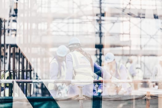 Construction site with team of construction laborers working on scaffold.