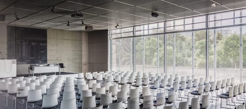 Interior of empty contemporary conference hall with white chairs.