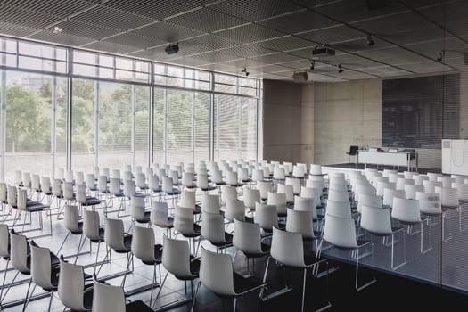 Interior of empty contemporary conference hall with white chairs.