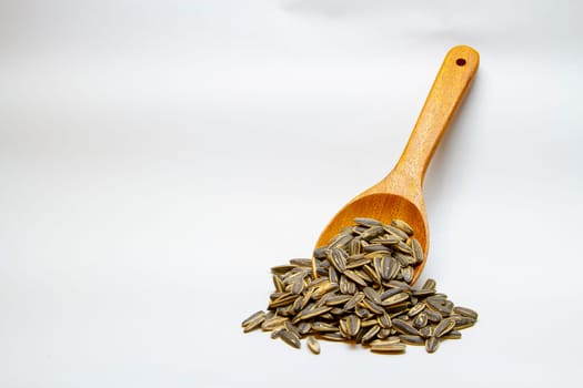Dried sunflower seeds in the wooden spoon on white background.