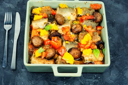 Fried hake fish grilled with orange, tomato and mushrooms. Close up