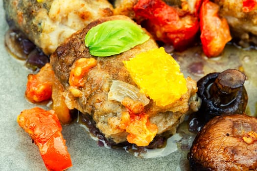 Fried hake fish grilled with orange, tomato and mushrooms. Close up