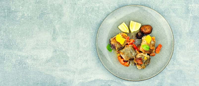 Fried hake fish grilled with orange, tomato and mushrooms. Close up