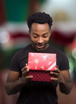 young man receiving a gift and opening box christmas night surprise holiday surprise decorated window