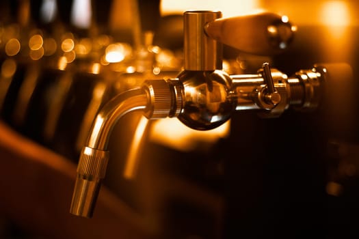 Creatively blurred image of faucets in beer pub with defocused bokeh and artistic digital noise. Golden row of taps in tap room. Bar background image