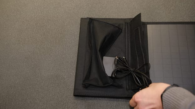 Hands open shows portable solar panel usb output mutlipurpose cable charging smartphone, power bank, watches, laptops gray background. Clean energy for using in camping or at home when NO electricity