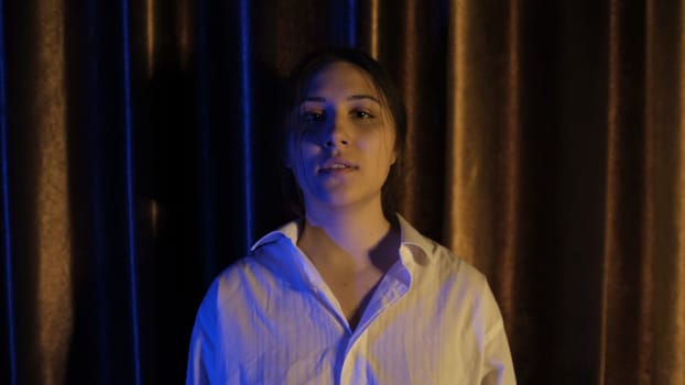 Nervous woman in white shirt in blue and yellow light breathing deeply with focus breathing, calming down after quarrel, Concept of abuse in relationships. Mental and physical violance woman.