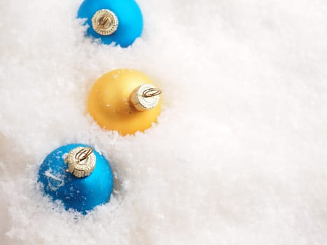 Blue and golden vintage Christmas baubles in the snow with space for text, seasonal backdrop