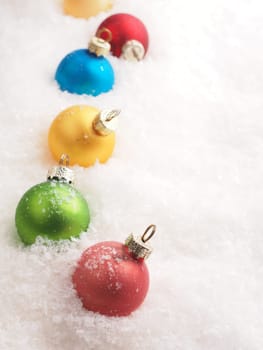 Colorful vintage Christmas baubles in the snow with space for text, seasonal backdrop
