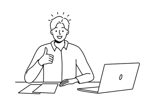 Smiling man at office desk show thumb up