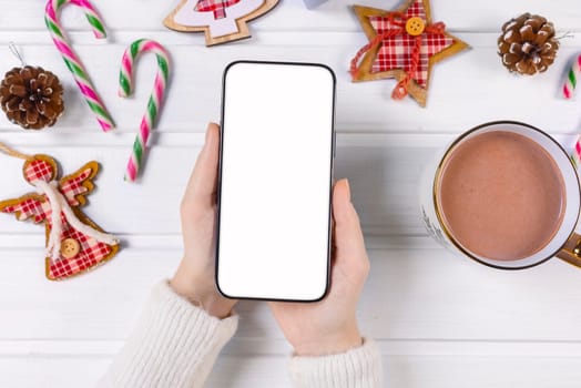 Close up woman holding phone with empty white screen mockup over decorated festive background, celebrating Christmas, customer shopping online, purchasing gifts, browsing gadget apps