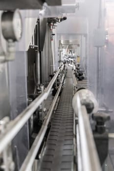 Industrial bottling machine at modern wine factory in Italy, close up. Automatic conveyor line for wine-producing