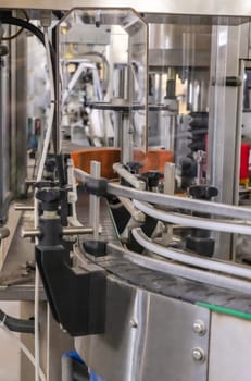 Industrial bottling machine at modern wine factory in Italy, close up. Automatic conveyor line for wine-producing