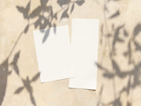 Blank paper cards on a concrete table decorated with olive branches with fruits top view, mockup. Sunny summer mediterranean scene with wedding stationery set. Flat lay with place for text