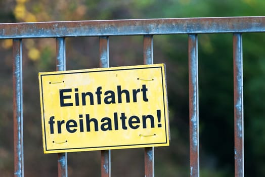 Einfahrt bitte freihalten. (keep entrance clear) Old historical iron gate. White sign with the inscription "keep entrance clear"". The Background is blurred"