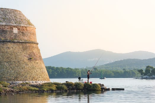 yound man is sitting and fishing on canal of sveti ante in sibenik croatia
