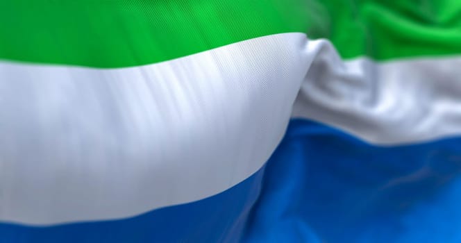 Detail of the Sierra Leone national flag waving in the wind. The Republic of Sierra Leone is a West African state. Fabric textured background. Selective focus. 3D illustration
