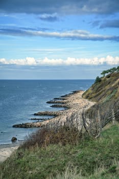 Hundested, Denmark on the cliff overlooking the sea. Baltic Sea coast, grassy meadow, beach. Clouds on horizon. Landscape photo from Scandinavia.