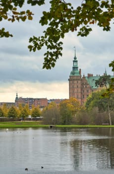 Frederiksborg castle park with created lake, in the background the castle. Bright colors of the leaves. Walk in Denmark