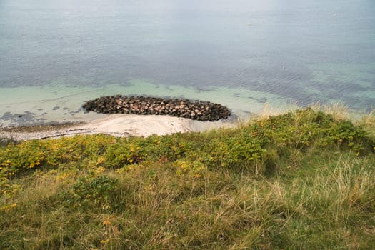 Hundested, Denmark on the cliff overlooking the sea. Baltic Sea coast, grassy meadow, beach. Clouds on horizon. Landscape photo from Scandinavia.