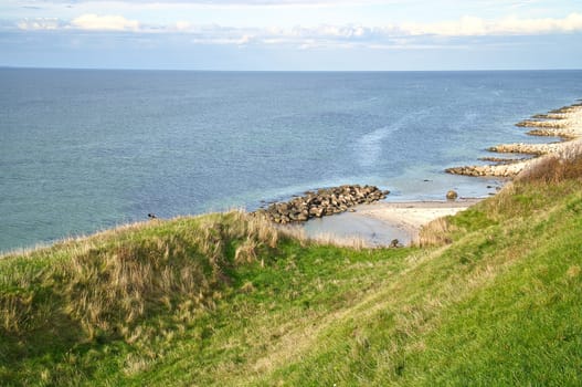 Hundested, Denmark on the cliff overlooking the sea. Baltic Sea coast, grassy meadow, beach. Clouds on horizon. Landscape photo from Scandinavia.