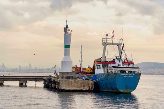 Old cargo ship docked beside a small beacon, at Kinaliada island harbour, marmara sea, near Istanbul, Turkey, at sunrise, in a summer day