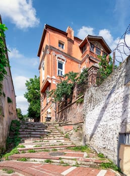 Walkway with red bricks stairs leading to old traditional building and trees, in a sunny day, Balat district, Istanbul, Turkey