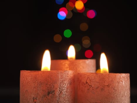 Three Advent candles burning with Christmas lights bokeh and space for text